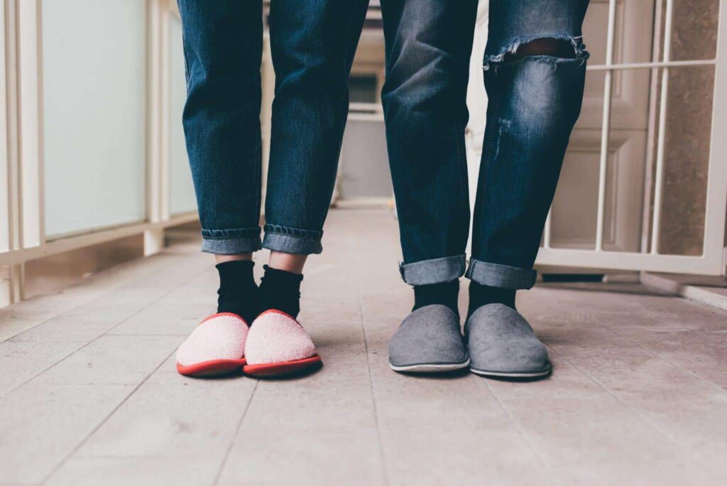 Feet of a couple of young man and woman wearing slippers indoor apartment