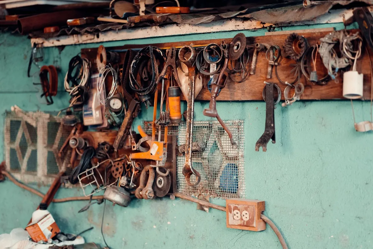 Vintage tools hang on a rustic wall, evoking a sense of nostalgia for skilled plumbing work.